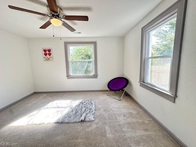 spare room featuring ceiling fan, light colored carpet, and a wealth of natural light