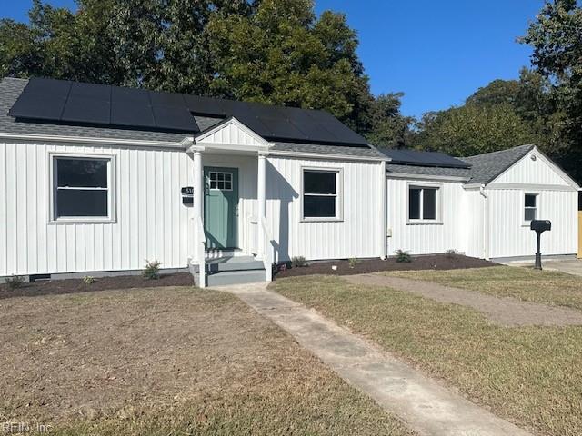 view of front facade with solar panels and a front lawn