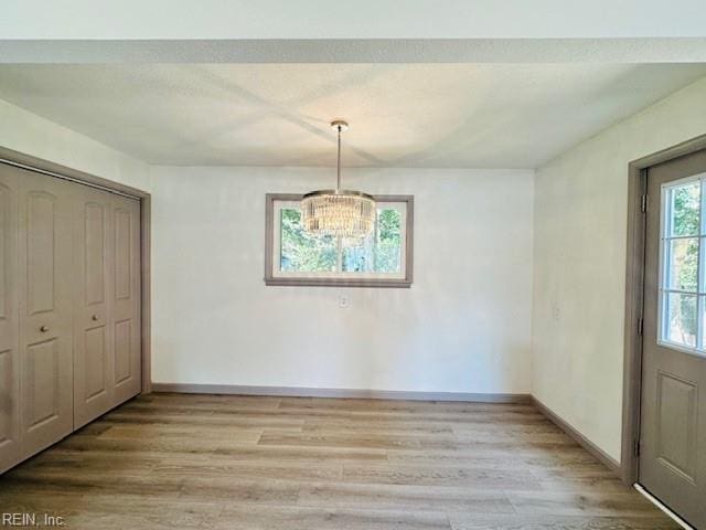 unfurnished dining area featuring a notable chandelier and hardwood / wood-style floors