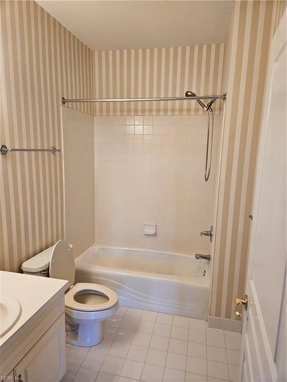 full bathroom featuring tiled shower / bath, tile patterned flooring, vanity, and toilet