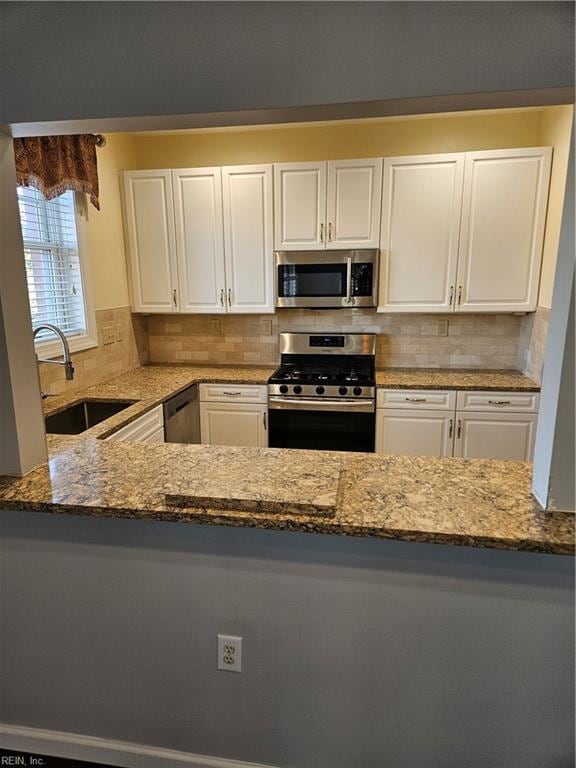 kitchen with decorative backsplash, appliances with stainless steel finishes, sink, stone countertops, and white cabinetry