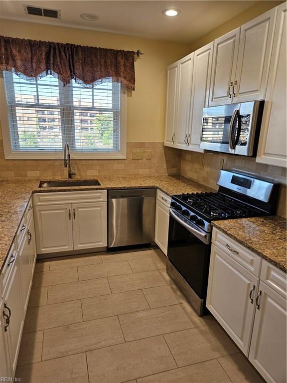 kitchen with backsplash, white cabinetry, sink, and stainless steel appliances