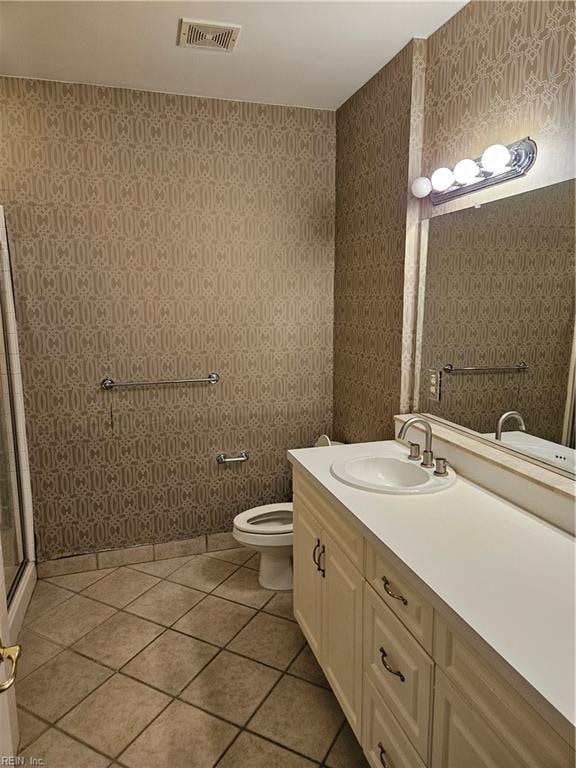 bathroom featuring tile patterned flooring, vanity, toilet, and a shower with door