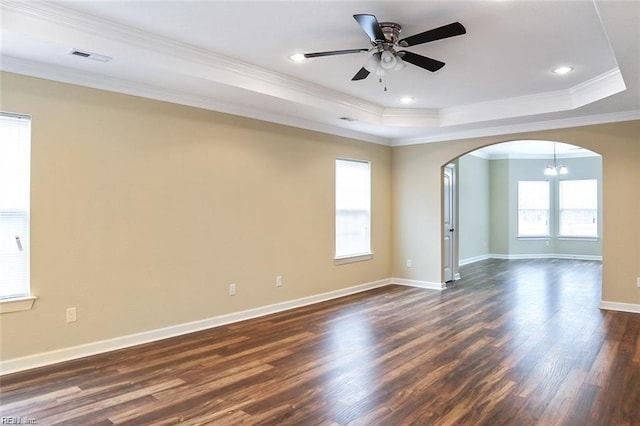 spare room with dark wood-type flooring, ornamental molding, a tray ceiling, and ceiling fan with notable chandelier