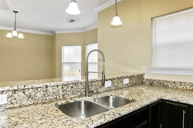 kitchen featuring crown molding, light stone countertops, sink, and pendant lighting