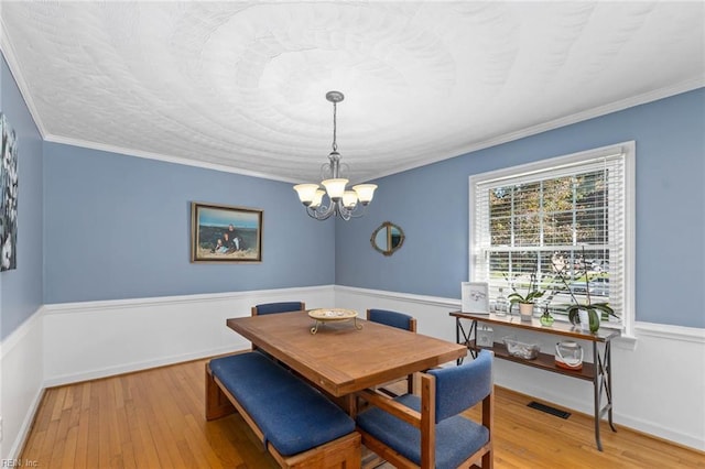 dining area with crown molding, hardwood / wood-style floors, and a notable chandelier