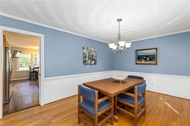 dining area with ornamental molding, hardwood / wood-style flooring, and an inviting chandelier