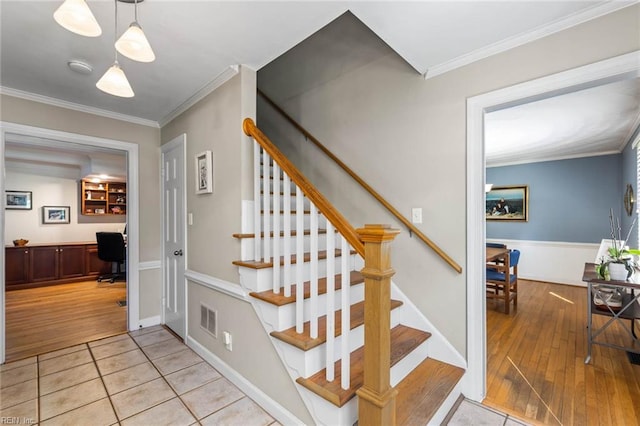 stairway with crown molding and wood-type flooring