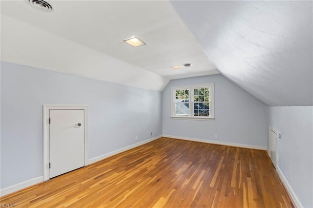 additional living space with vaulted ceiling and hardwood / wood-style floors