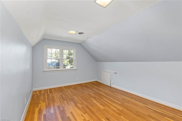 additional living space with light hardwood / wood-style floors and lofted ceiling