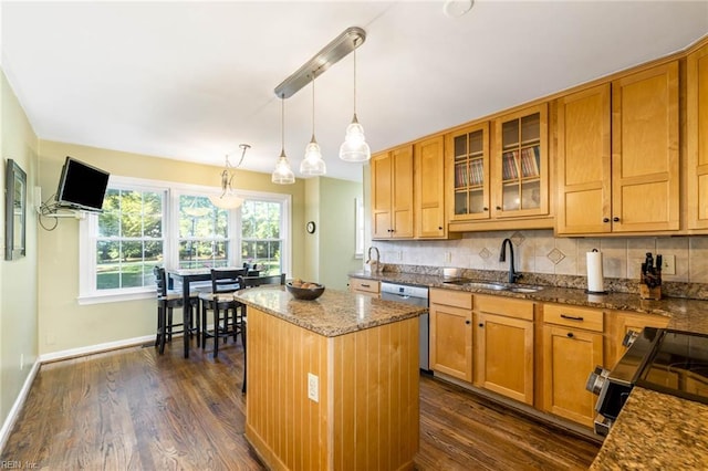 kitchen with appliances with stainless steel finishes, sink, a center island, dark hardwood / wood-style flooring, and pendant lighting