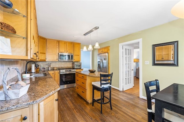 kitchen with sink, a kitchen island, appliances with stainless steel finishes, and dark hardwood / wood-style flooring