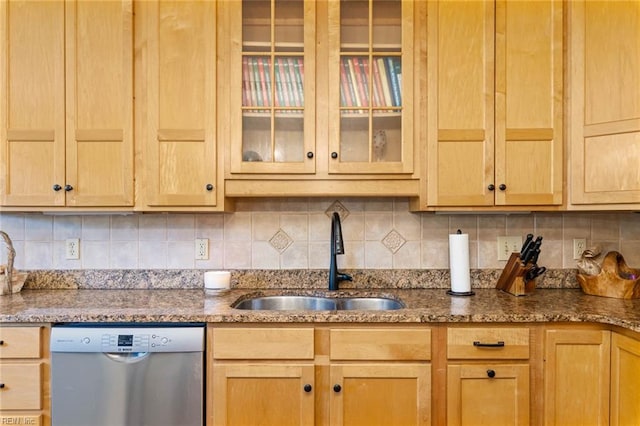 kitchen with stone counters, stainless steel dishwasher, sink, and backsplash