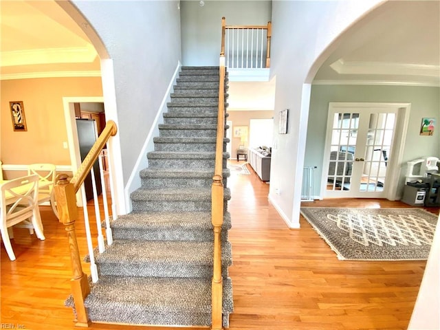 stairway featuring french doors, ornamental molding, and hardwood / wood-style floors