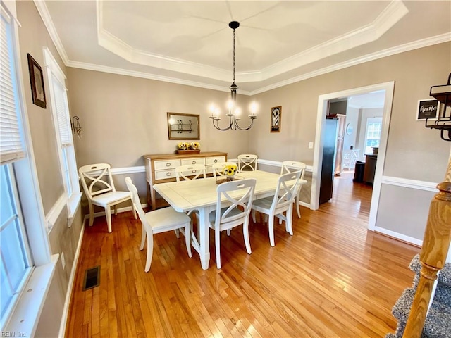 dining room with a tray ceiling and light hardwood / wood-style floors