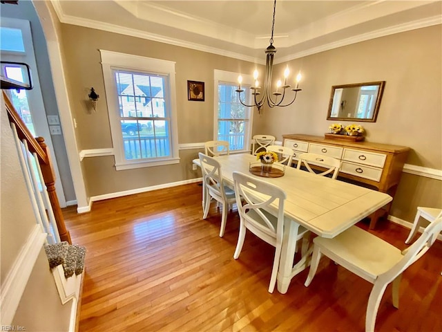 dining room featuring light hardwood / wood-style flooring, ornamental molding, a notable chandelier, and a tray ceiling