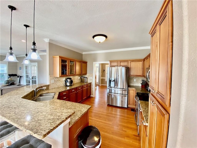 kitchen featuring kitchen peninsula, stainless steel appliances, backsplash, a kitchen bar, and decorative light fixtures