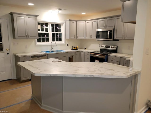 kitchen with gray cabinetry, light stone countertops, sink, kitchen peninsula, and stainless steel appliances