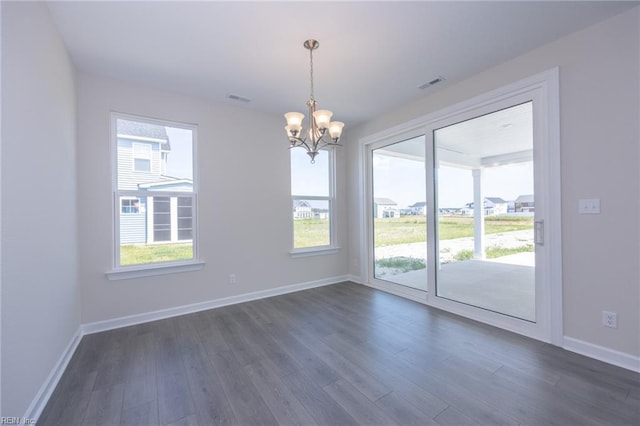 unfurnished dining area featuring dark hardwood / wood-style floors, a healthy amount of sunlight, and a chandelier