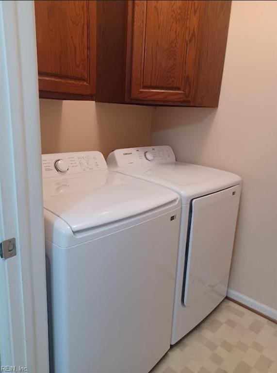 clothes washing area with washing machine and clothes dryer and cabinets