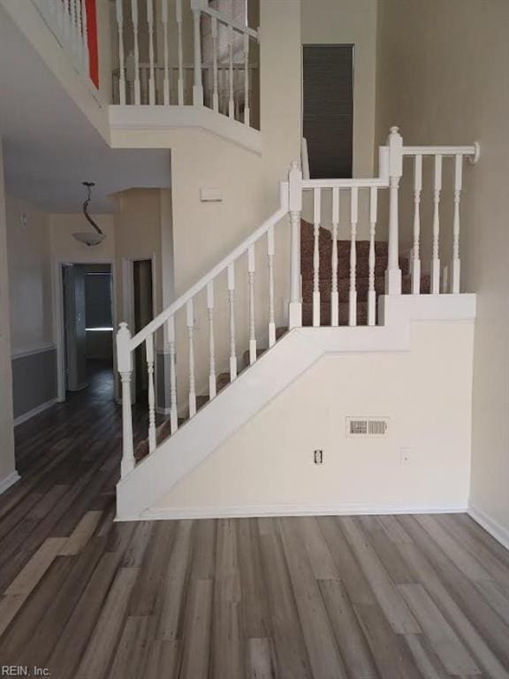 stairway with a high ceiling and hardwood / wood-style floors