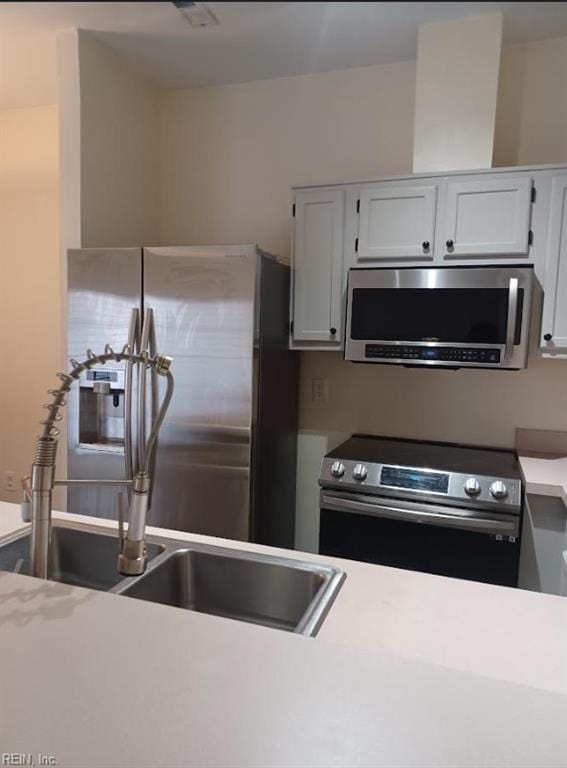 kitchen featuring stainless steel appliances, sink, and white cabinets