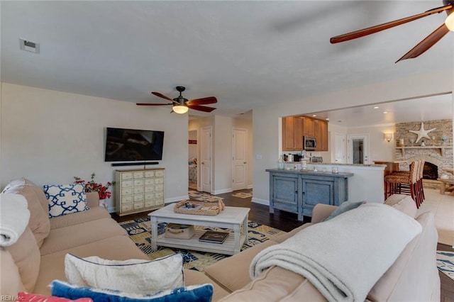 living room featuring ceiling fan, hardwood / wood-style flooring, and a fireplace