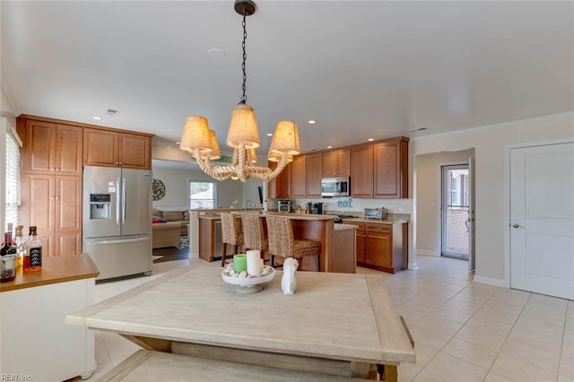 kitchen featuring a chandelier, light tile patterned flooring, stainless steel appliances, pendant lighting, and a center island