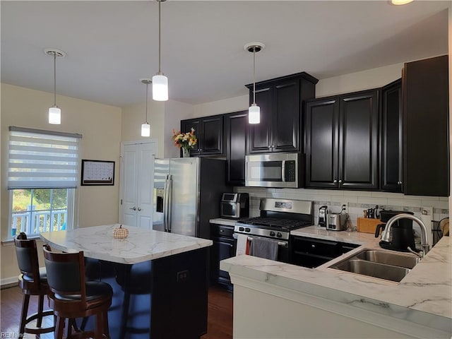 kitchen featuring decorative backsplash, hanging light fixtures, appliances with stainless steel finishes, dark hardwood / wood-style floors, and sink