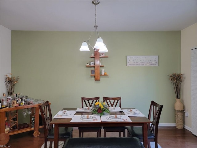 dining room with dark wood-type flooring and a notable chandelier