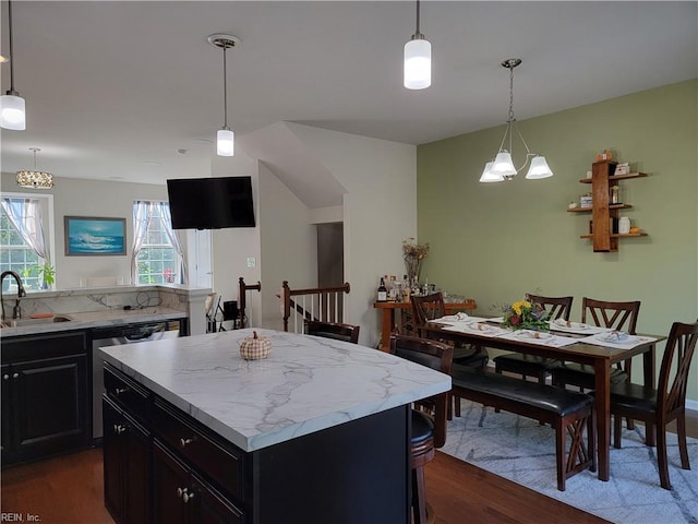 kitchen with sink, a kitchen island, stainless steel dishwasher, pendant lighting, and dark wood-type flooring