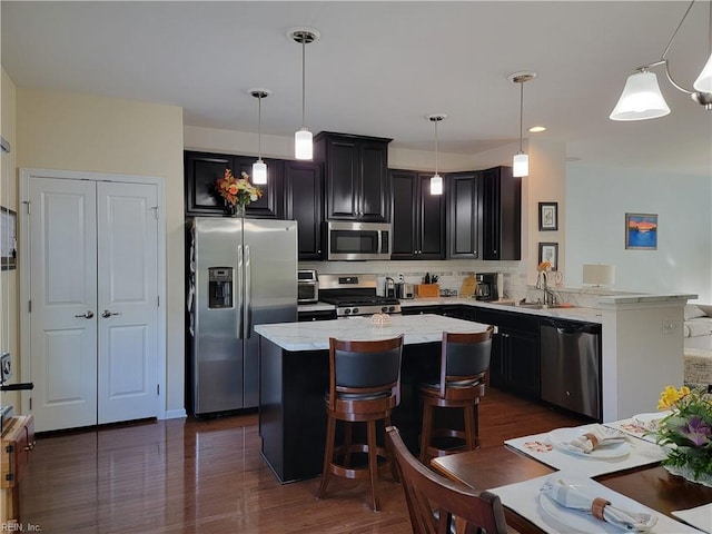 kitchen featuring appliances with stainless steel finishes, light stone countertops, and hanging light fixtures