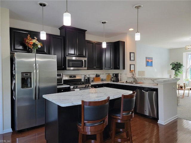 kitchen featuring decorative light fixtures, light stone countertops, stainless steel appliances, and dark wood-type flooring