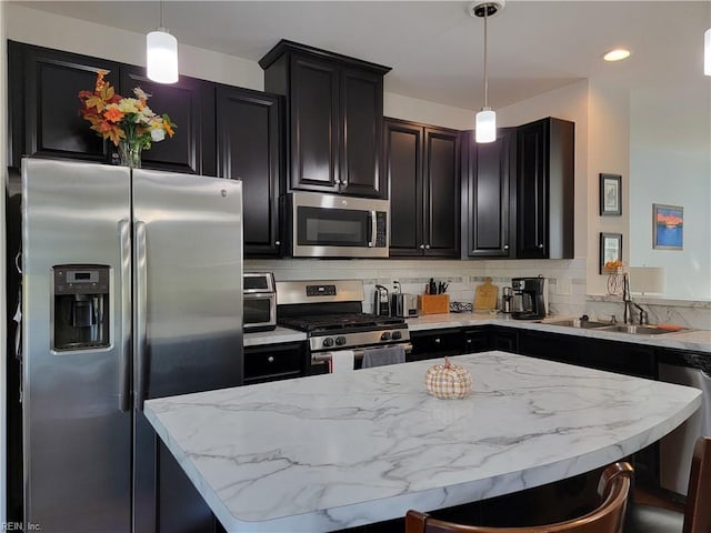 kitchen featuring decorative backsplash, a breakfast bar area, appliances with stainless steel finishes, sink, and decorative light fixtures