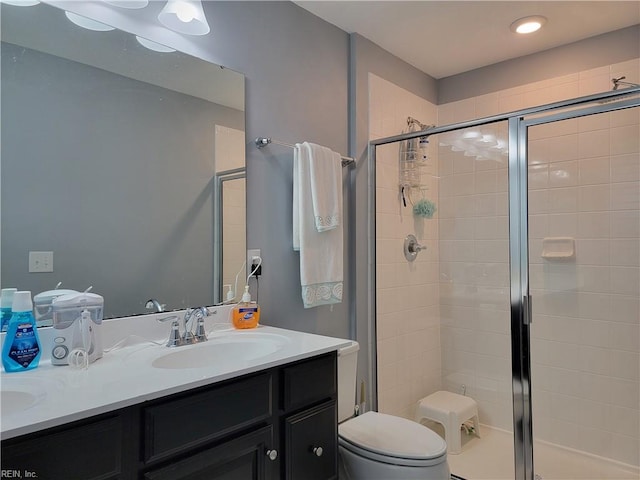 bathroom featuring vanity, a shower with shower door, and toilet