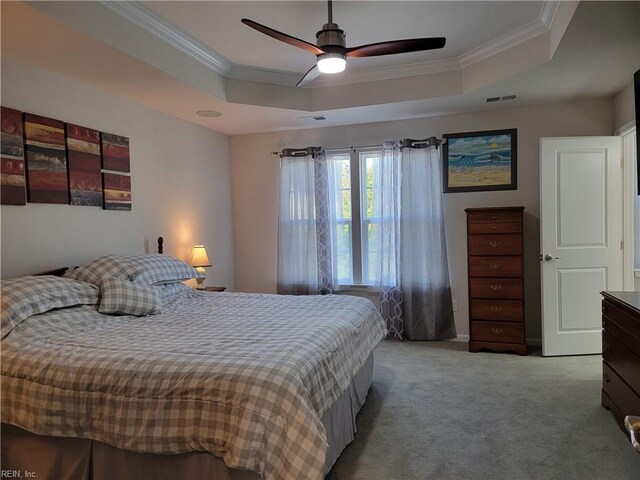 carpeted bedroom with ornamental molding, ceiling fan, and a raised ceiling