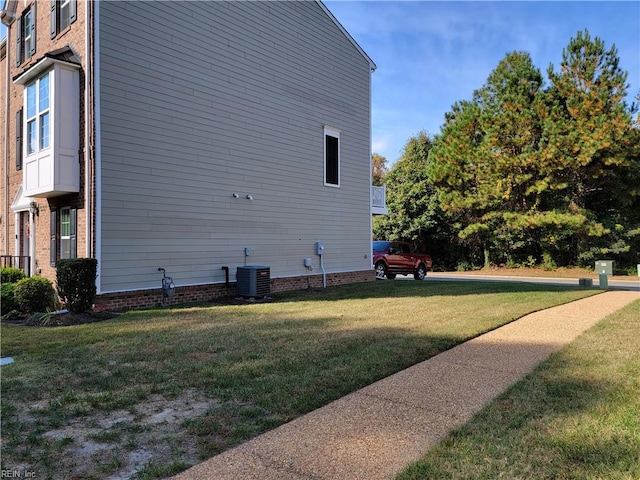 view of side of property featuring central air condition unit and a lawn