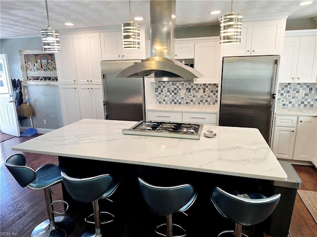 kitchen with dark hardwood / wood-style floors, hanging light fixtures, stainless steel appliances, a center island, and white cabinets