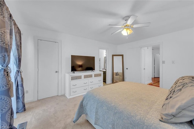 carpeted bedroom with ensuite bathroom and ceiling fan