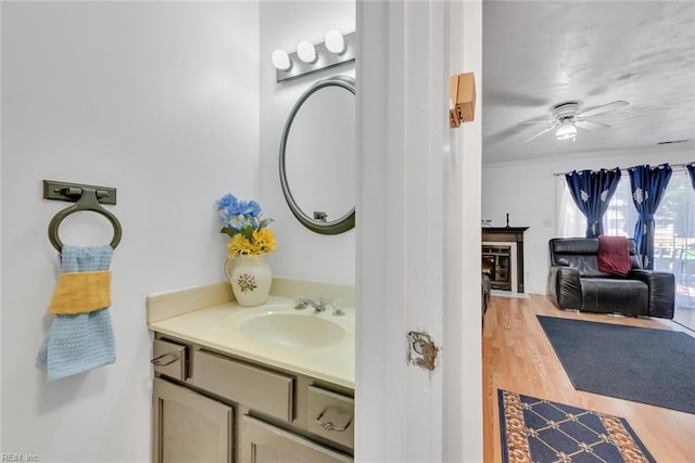 bathroom with vanity, a fireplace, hardwood / wood-style flooring, and ceiling fan