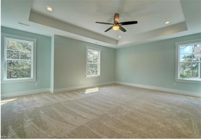 carpeted spare room with ceiling fan and a tray ceiling