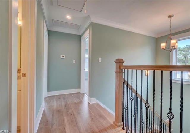 hallway with light hardwood / wood-style flooring, ornamental molding, and a notable chandelier