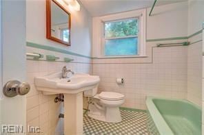 bathroom featuring tile walls, shower with separate bathtub, and toilet