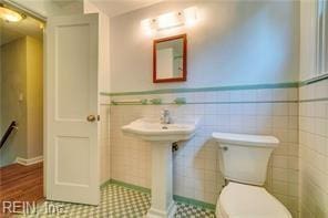 bathroom featuring toilet and tile walls