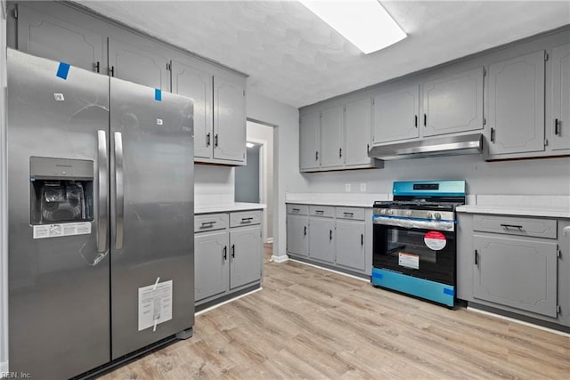 kitchen with gray cabinetry, stainless steel appliances, and light hardwood / wood-style flooring