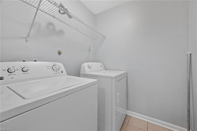 laundry area with washer and clothes dryer and light tile patterned flooring