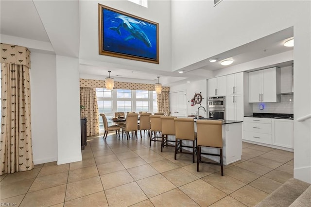 kitchen featuring white cabinets, light tile patterned floors, a breakfast bar, pendant lighting, and stainless steel double oven