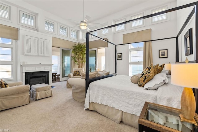 bedroom with ceiling fan, a high ceiling, and light colored carpet