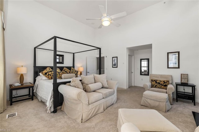 bedroom with a towering ceiling, light colored carpet, and ceiling fan