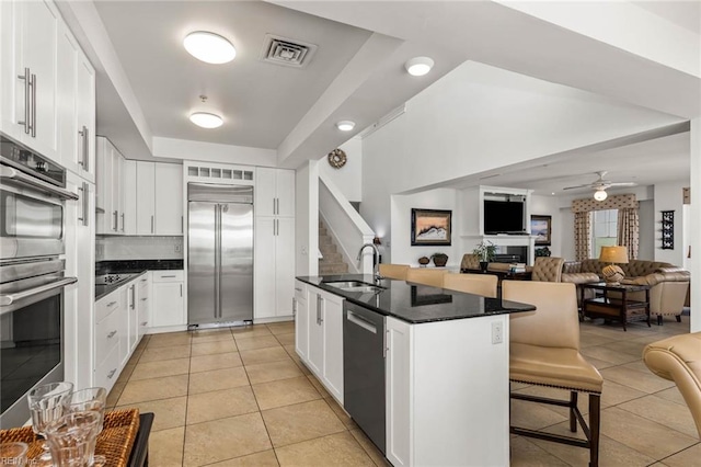 kitchen with a kitchen breakfast bar, sink, white cabinetry, appliances with stainless steel finishes, and ceiling fan